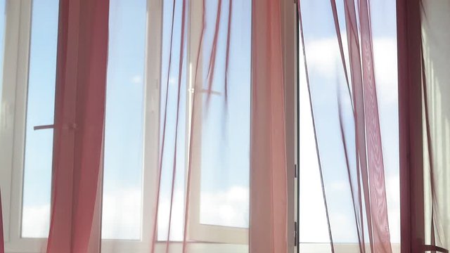 red curtains of the window close up blowing in the wind