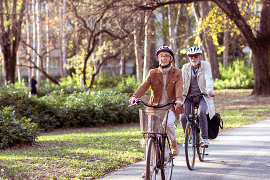 Senior couple with bycicles and helmets in park