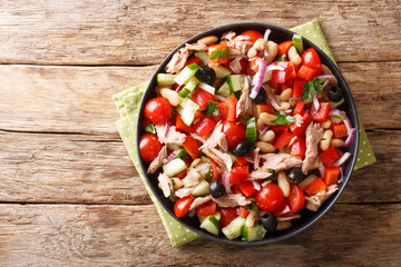 Serving of fresh salad with tuna, vegetables, olives and beans close-up in a plate. horizontal top view