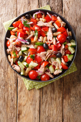 tuna salad with tomatoes, onions, peppers, cucumbers and beans close-up in a plate. vertical top view
