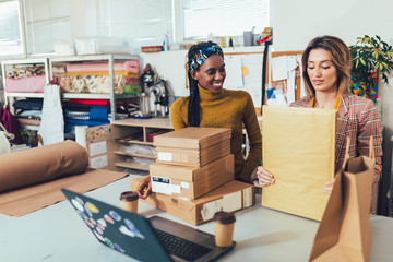 Sales Online. Working women at their store. They accepting new orders online and packing...