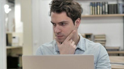 Pensive Creative Man Thinking and Working on Laptop