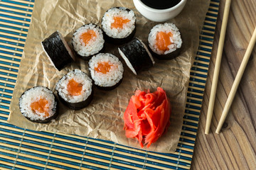Sushi-Tuna and salmon maki roll with ginger and soy sauce on a bamboo napkin with wooden sticks. Fresh Asian seafood food