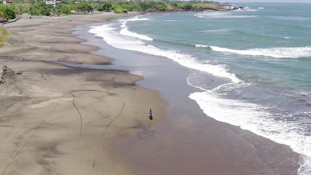 Dirt Bike Rider Fun Ride On A Sandy Beach In Bali, Indonesia With Calm Waves Breaking, Top Down Aerial View.