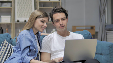 Young Couple Discussing Online on Laptop at Home