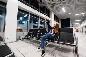 A young successful woman uses a smartphone in the waiting area at the airport.