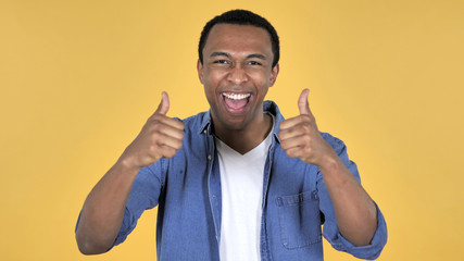 Young African Man Gesturing Thumbs Up Isolated on Yellow Background