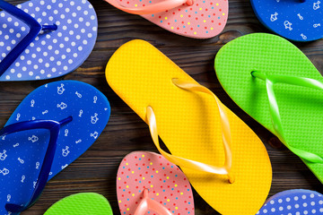 a lot of flip flop colored sandals, summer vacation on wooden background, copy space top view