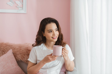 woman holding cup smiling into camera in living room