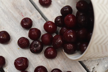 a fallen mug and scattered frozen cherries on a wooden table
