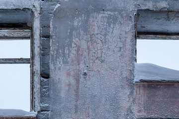 Old concrete wall with broken windows. Abandoned district. Russian far North