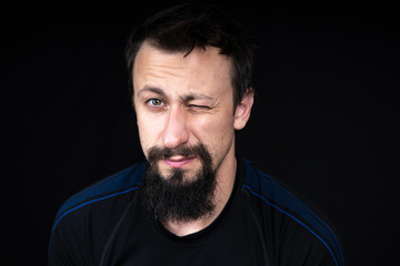 Fototapeta premium a close up portrait of a young man with beard in dark clothes on a dark background