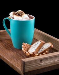 Cocoa with marshmallow on a wooden board with almond crackers, on a dark background