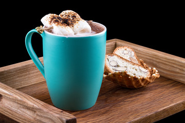 Cocoa with marshmallow on a wooden board with almond crackers, on a dark background