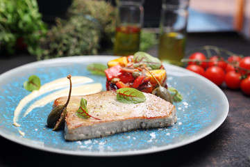 Tuna steak with fried vegetables. A plate with an appetizing dish. Application suggestion. Culinary photography, food stylization.