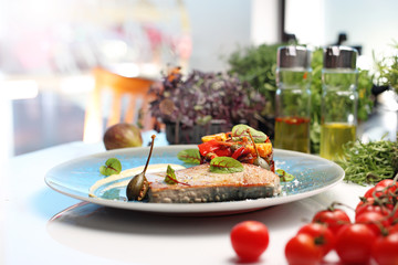 Tuna steak with fried vegetables. A plate with an appetizing dish. Application suggestion. Culinary photography, food stylization.