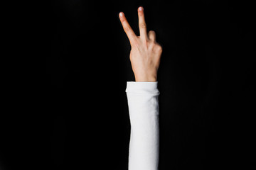 Girl hand with peace sign on black background