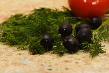 a sprig of dill with olives on a piece of fresh pita bread