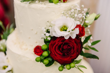Decorated with red roses and white tsetets wedding cream three-tier cake