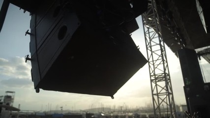 day shot close up of professional big speakers at an outdoor music live stage slow movement of camera, beautiful background with sail boats and sunlight