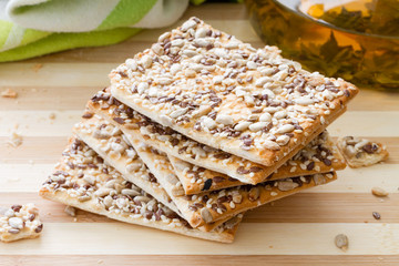 Square crackers with flax, sesame and sunflower seeds on cutting board
