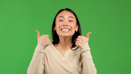 Asian model showing thumbs up. Excited beautiful woman on isolated background.
