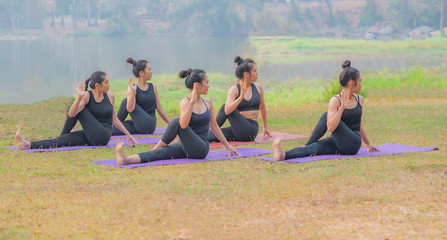 Woman group of  attending a yoga class in a lakeside garden.