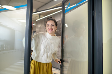 Young woman standing at the door, smiling happily