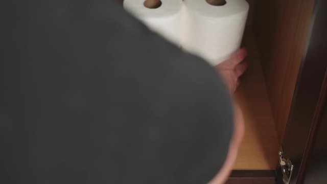 Man stockpiles toilet paper, white American hoarding toilet tissue, Toilet paper stash, Man hides toilet paper in preparation for Coronavirus COVID-19. Stationary camera shot showing man with TP