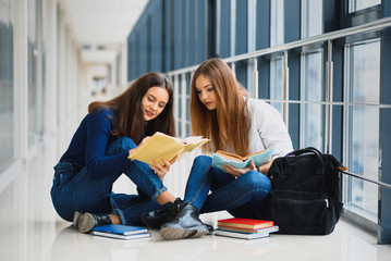 Female students sitting on the floor and reading notes before exam