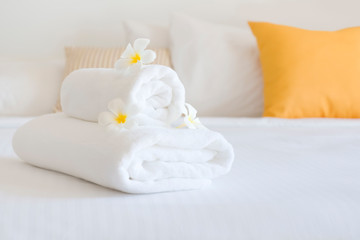 Fototapeta na wymiar Clean white spa towels and flowers in blurred bedroom interior