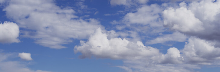 White fluffy clouds in blue sky. Panoramic view