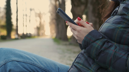Women's hands with a phone in the Park close-up. The woman uses the phone.