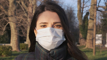Pandemic, portrait of a woman in a protective mask on the street.