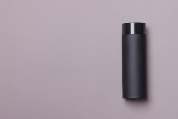 black thermos cup on grey paper background with copy space