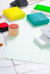 pencils, painting brushes, plasticine blocks and ink pads on white wood