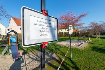 Verbotsschild und rot-weisses Absperrband an einem gesperrten Kinderspielplatz während der...