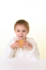 blonde girl with white clothes on a white background drinking orange juice