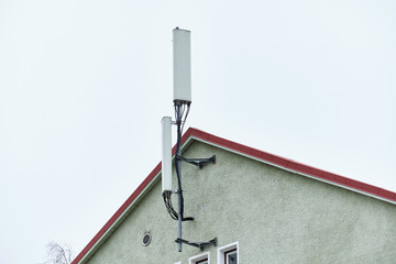 Cellular phone network telecommunication tower on the building roof.