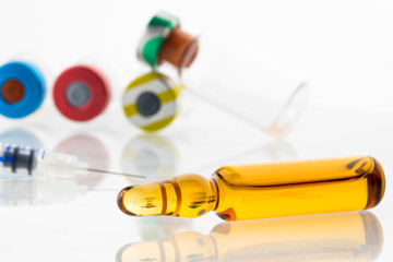 vaccine in brown glass ampoule on white background with medical equipment in background