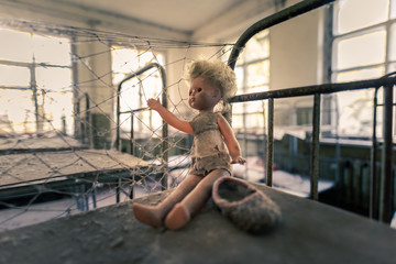 Dusty toy puppet sitting on bunk bed in abandoned kindergarden in Chernobyl Exclusion Zone