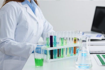 Fototapeta premium Chemical industry bulb with blue magenta pink liquid lab tubes stand on the table in the laboratory of liquid testing test development substances poisons additives stabilizers flavors house cleaning.