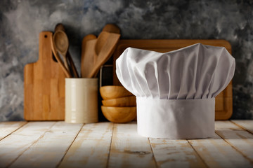 Fototapeta na wymiar White cook hat on desk and kitchen interior 