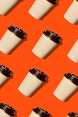 Coffee to go regular pattern made of photo on a lush lava background. Kraft paper cups with black lids and natural bright sun shadows. Lifestyle take away hot drinks concept. Trendy flatlay, top view.