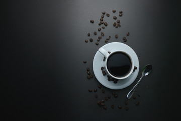 coffee cup with coffee beans on black office desk. flat lay. fine art. copy space for your text
