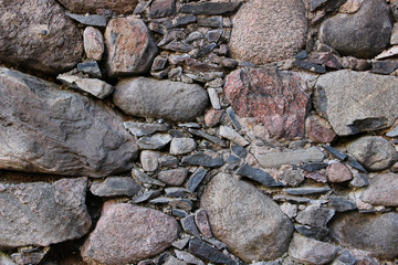 Old wall made of rocks. Medieval surface made of bricks. Texture of an old rocks sticked up with a cement.