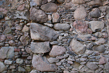 Old wall made of rocks. Medieval surface made of bricks. Texture of an old rocks sticked up with a cement.