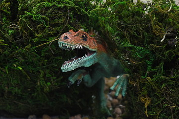 toy dinosaur makes its way through the moss