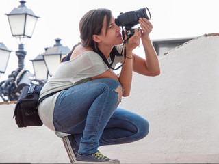 Joven fotógrafa agachada para sacar una foto