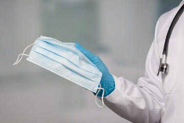 close up of doctor's hand in medical gloves shows medical face mask for protection against infection